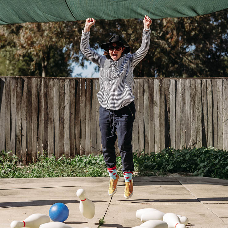 Lady jumping into the air after knocking over bowling pins